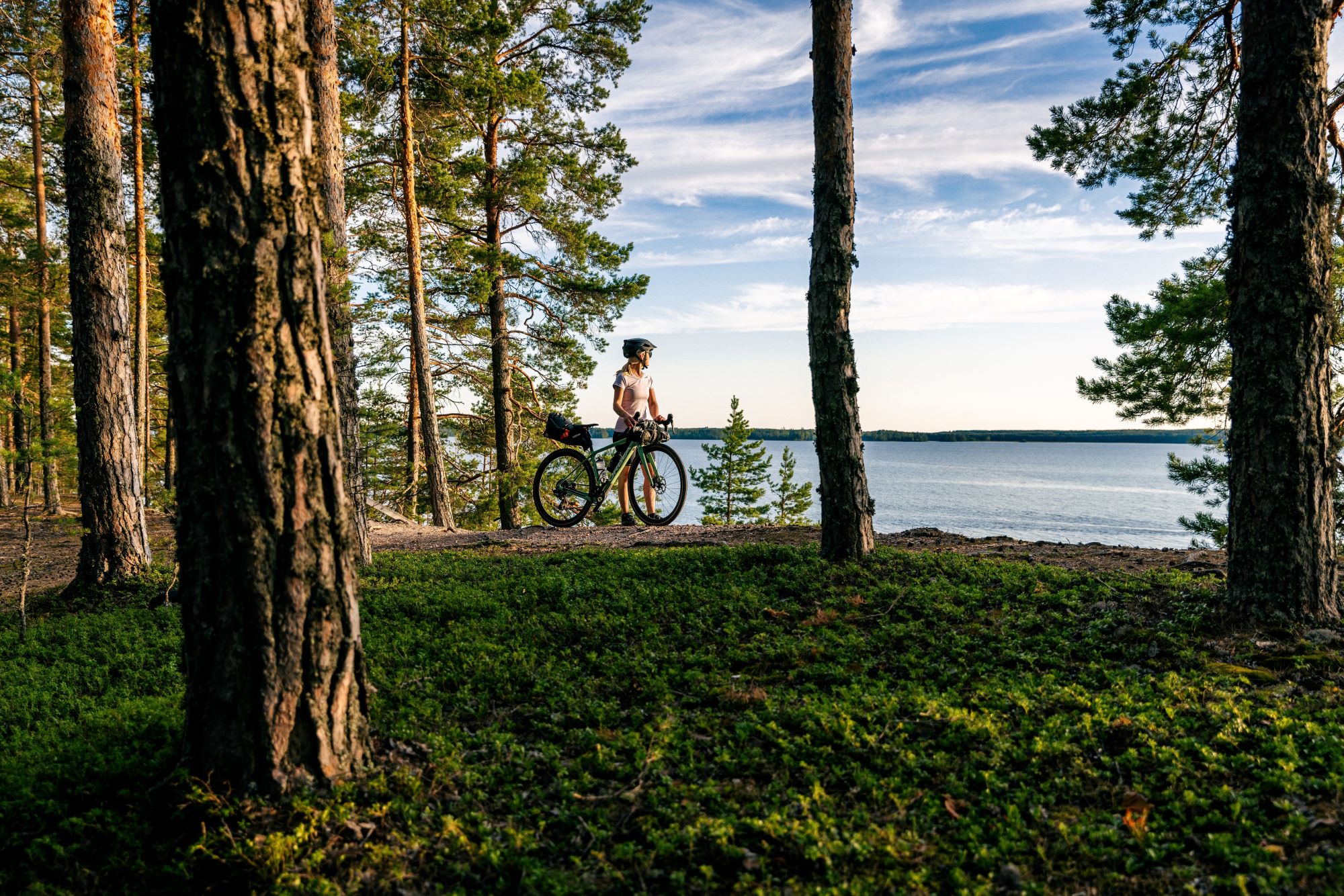 Pyöräilijä järviluontomaisemissa.